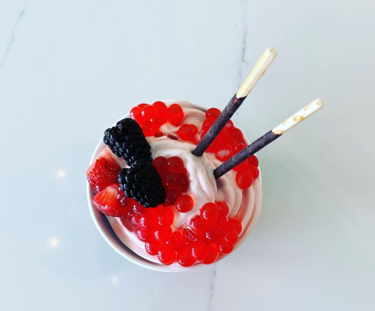 A photo from above of a bowl of frozen yogurt from Olo featuring Pockys, strawberries, blackberries, and strawberry popping pearls.