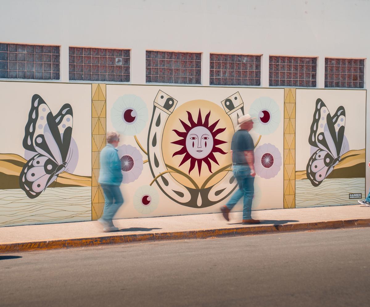 Visitors walking by SLO CAL's "Fly to Her" Mural in Cambria