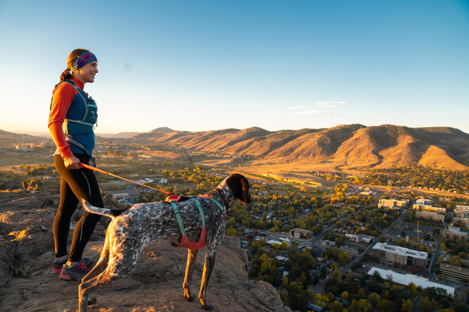 A runner and her dog standing on top of South Table Mountain looking out over Golden, Colorado