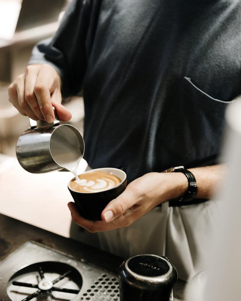 A barista pours a coffee drink at Little Bear Coffee