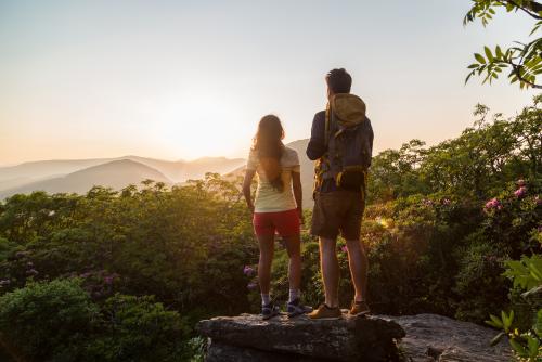 A couple watches the sun setting behind the western mountains from atop Craggy Gardens.