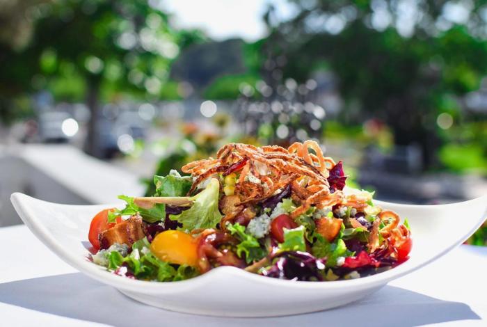 Large salad with many vegetables sitting on a plate.