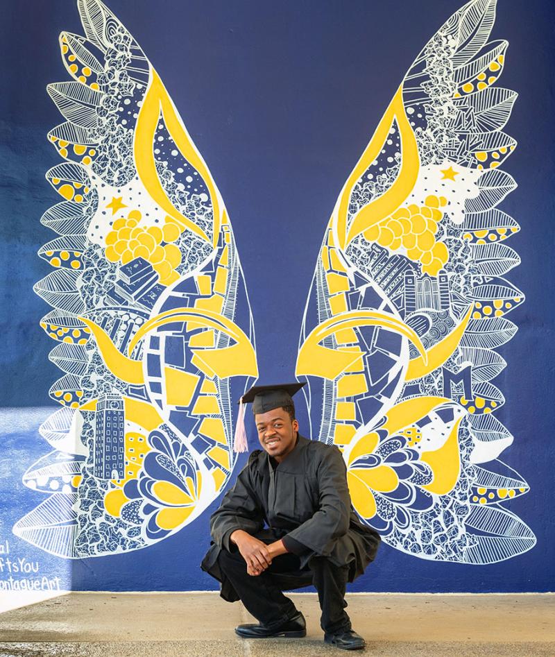 U-M Wings Mural with graduate posing