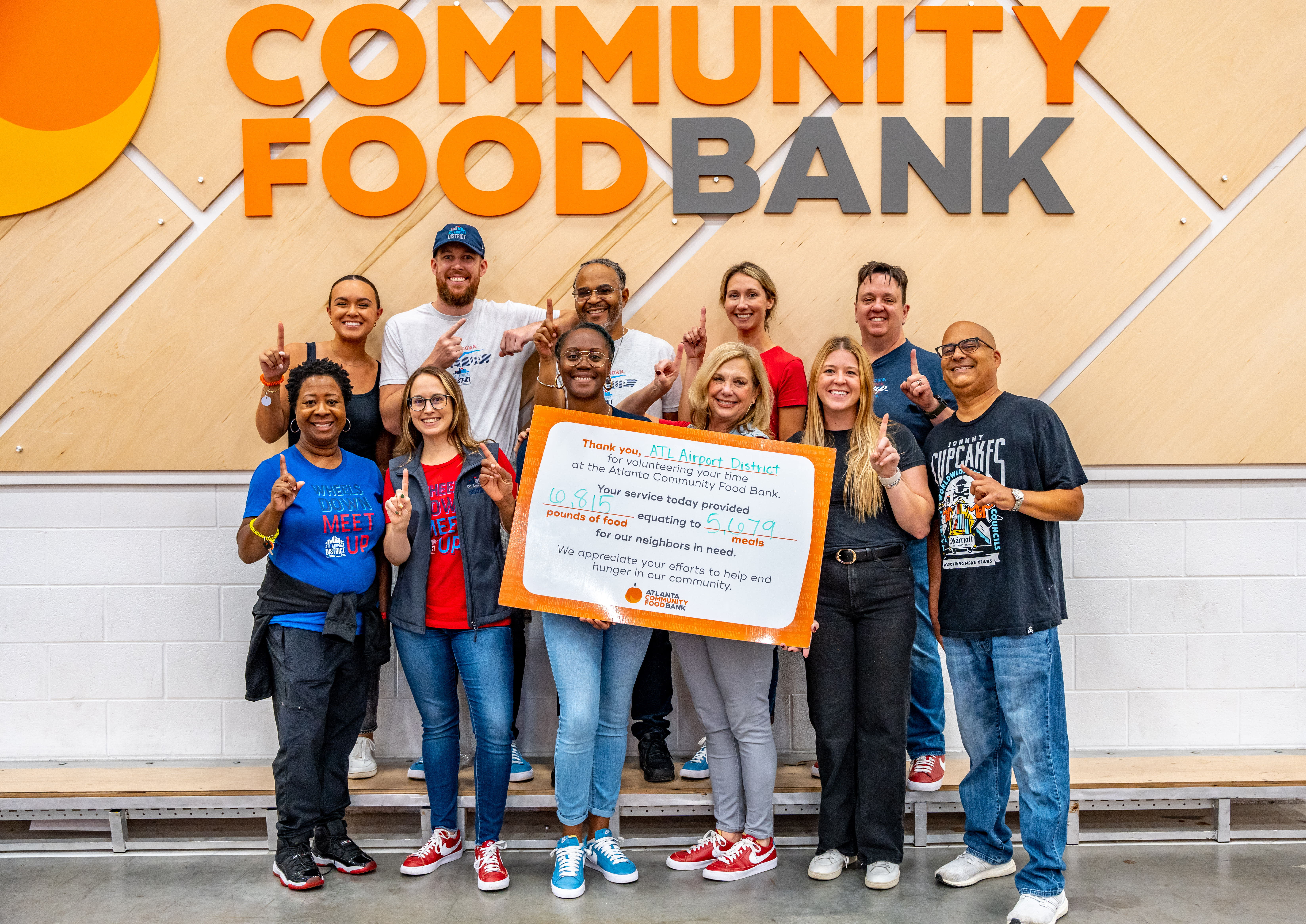 ATL Airport District poses at the Atlanta Community Food Bank holding a sign with the amount of meals sorted.