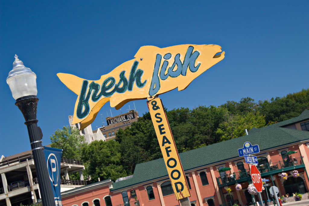 A sign for fresh fish and buildings in downtown Marquette Michigan.