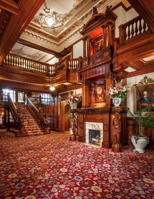 A large mansion-like room with wooden staircase, balcony and fireplace at the American Swedish Institute