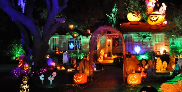 A house decorated with an assortment of Halloween themed yard decorations, lit in an eerie green color