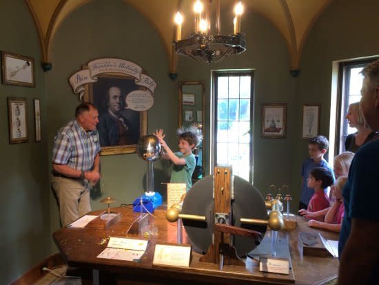 A young boy's hair stands from static electricity as he touches a round globe at The Bakken Museum