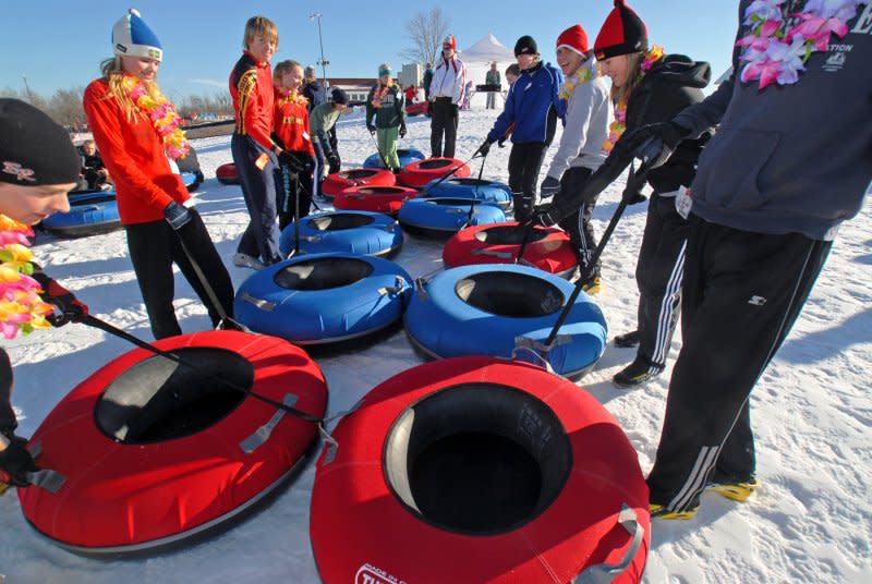 A group of people each standing next to blue and red snow tubes at Elm Creek Park Reserve