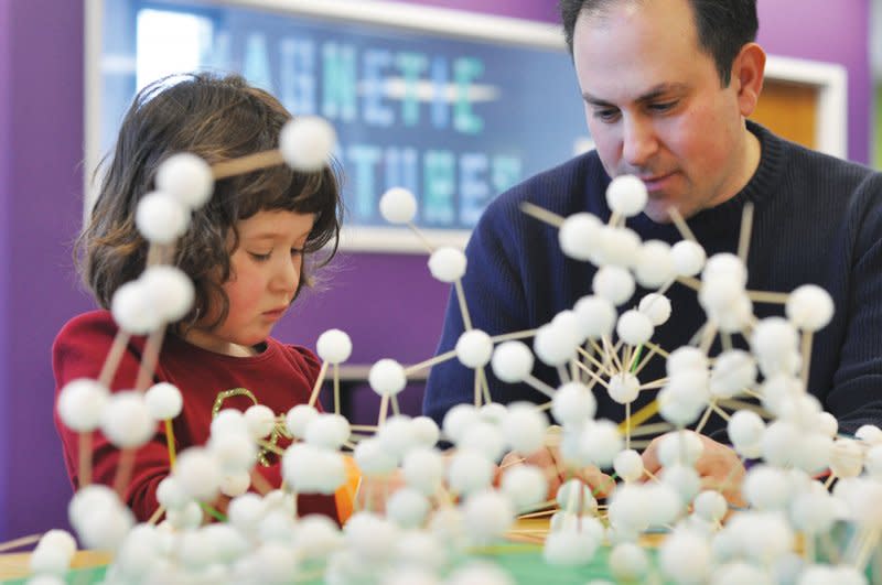 A man and young girl build with toy molecules at the The Works Museum