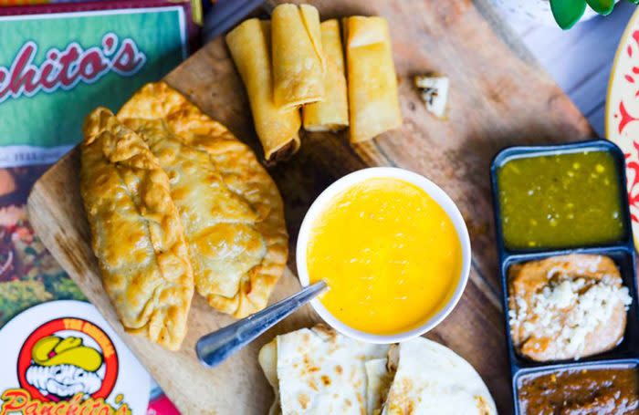 Empanadas on a board with queso and salsas