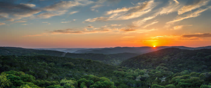 Explore San Antonio's Hill Country | This is an image of the Texas sunset behind mountains