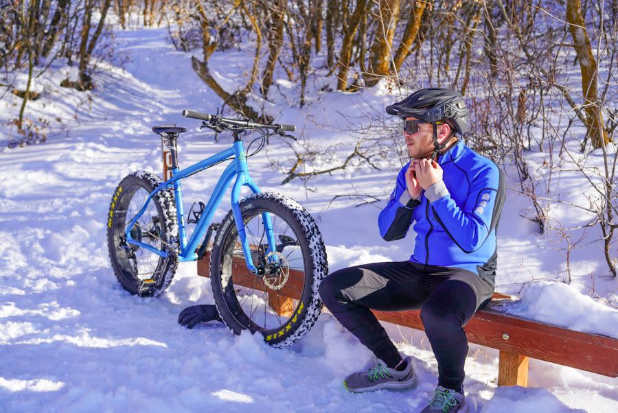 Man sitting on bench next to bike in snow