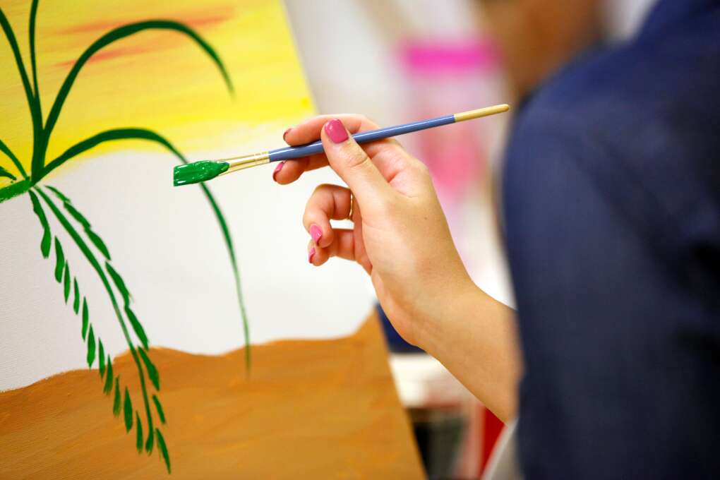 Tina Griffin paints a palm tree how to paint a palm tree during the Artsy Palm painting class at Yes You Canvas.