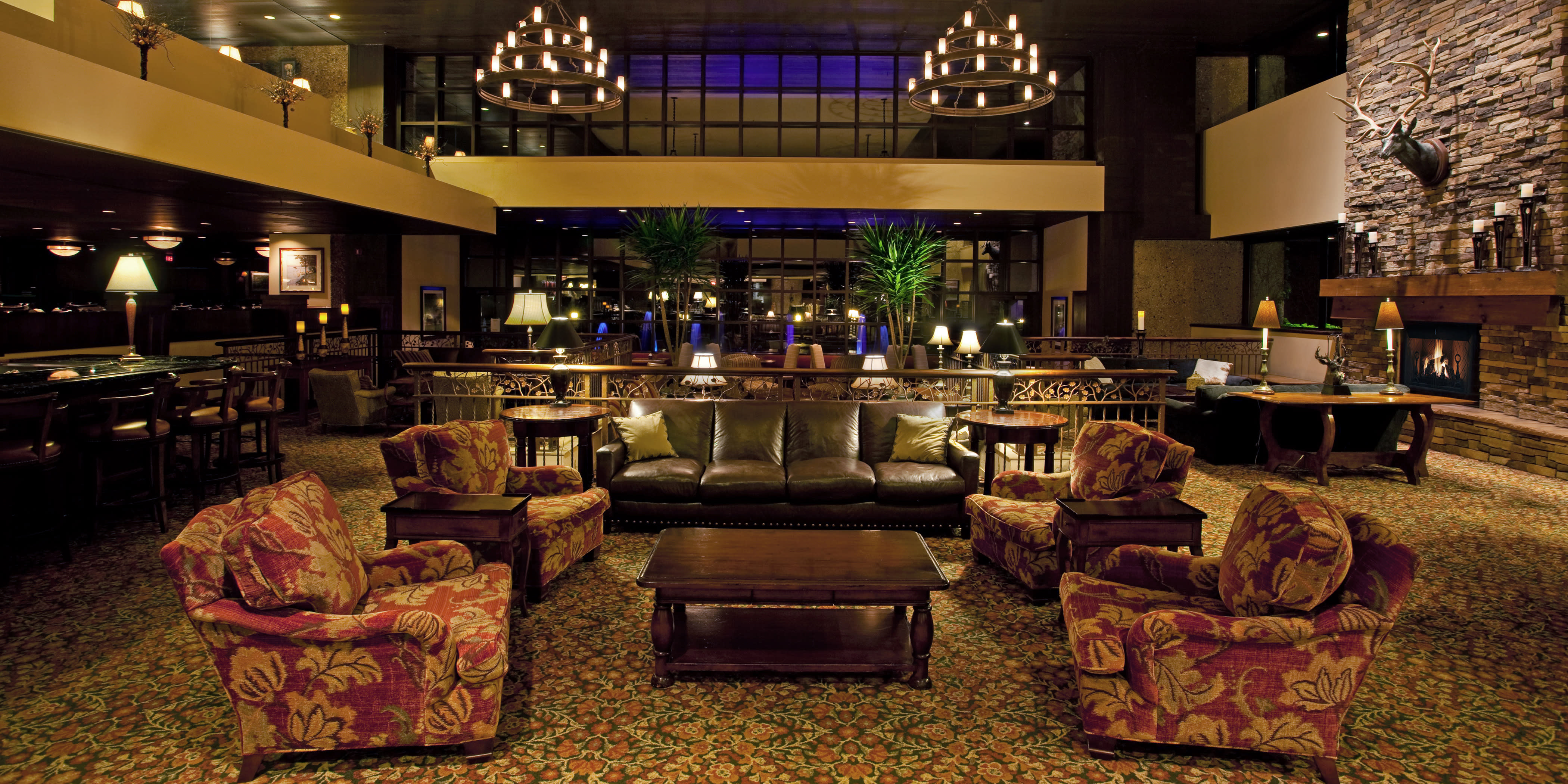 A large modern hotel lobby with a large stone fireplace adorn with a deer head