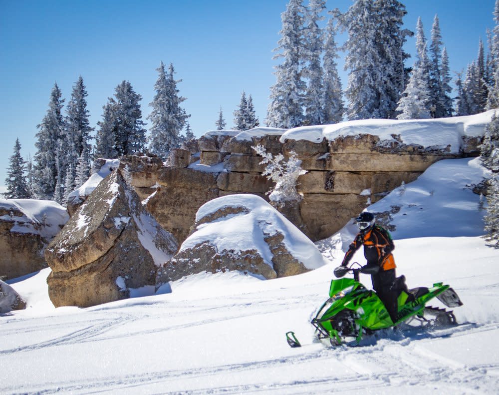 A visitor snowmobiles through Bighorn Mountains on a sunny day.