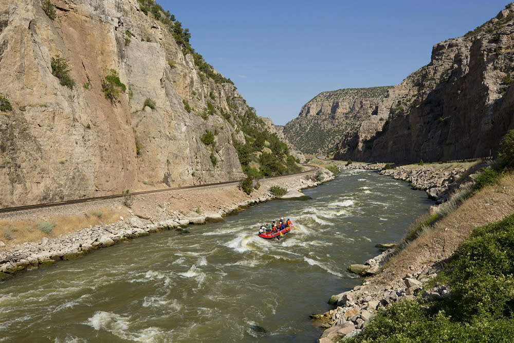 River running through canyon with white water rafters in the middle in Thermoplis, Wyoming