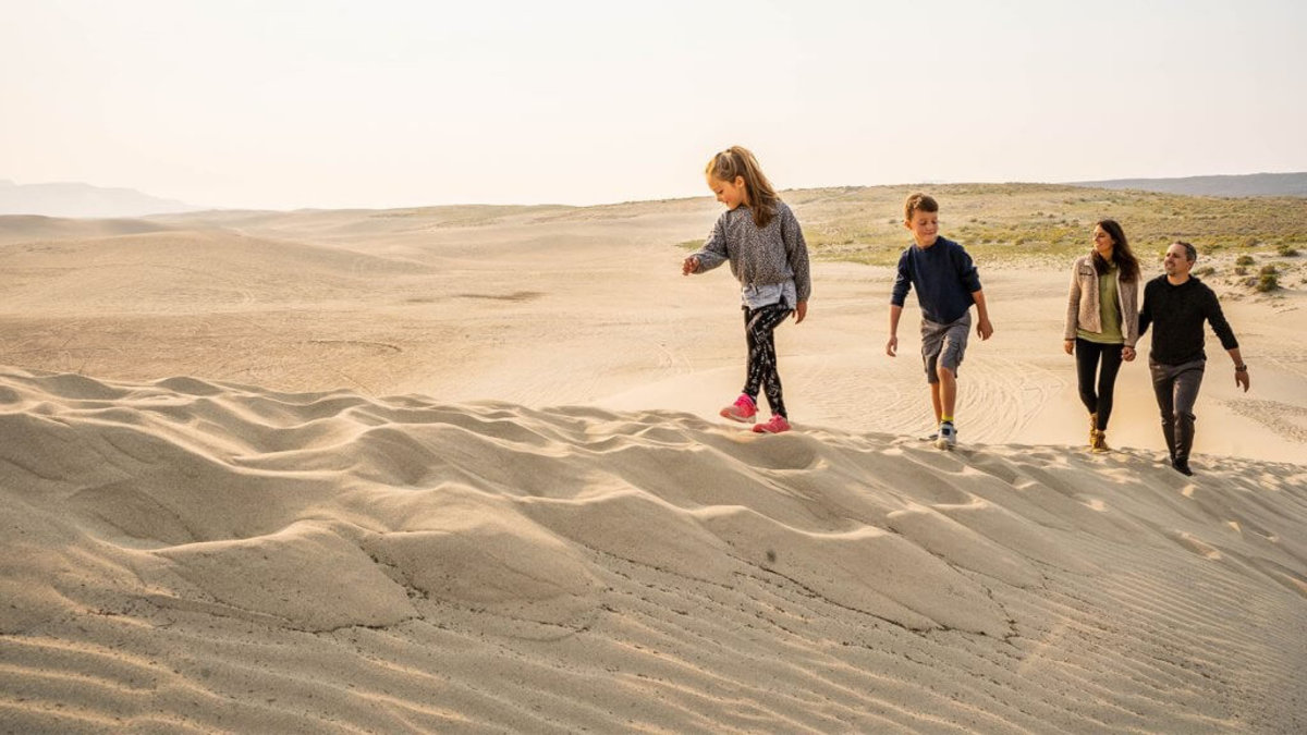 A family climbing a sand dune at the Killpecker Sand Dunes.