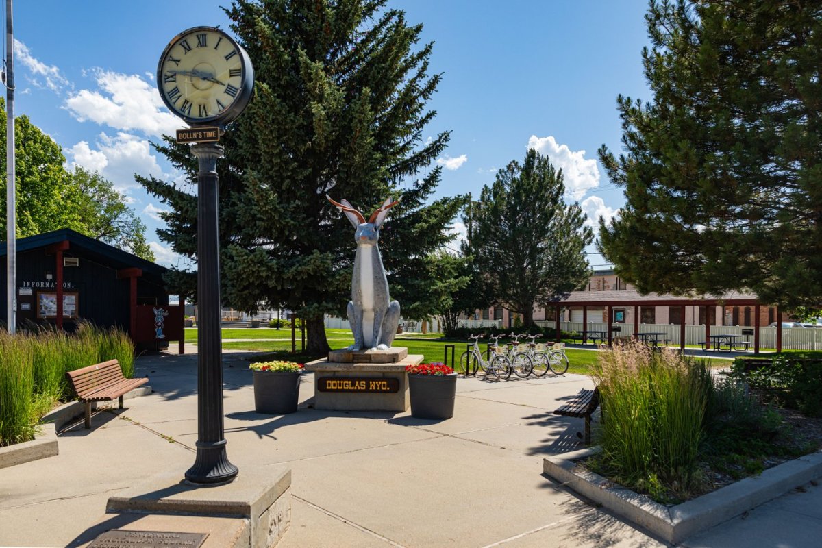 a standing clock tower and jackalope statue in a quaint park in Wyoming