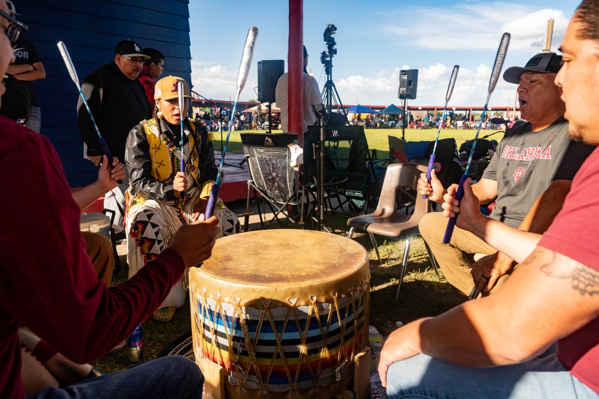 Men singing and playing a drum in a circle.