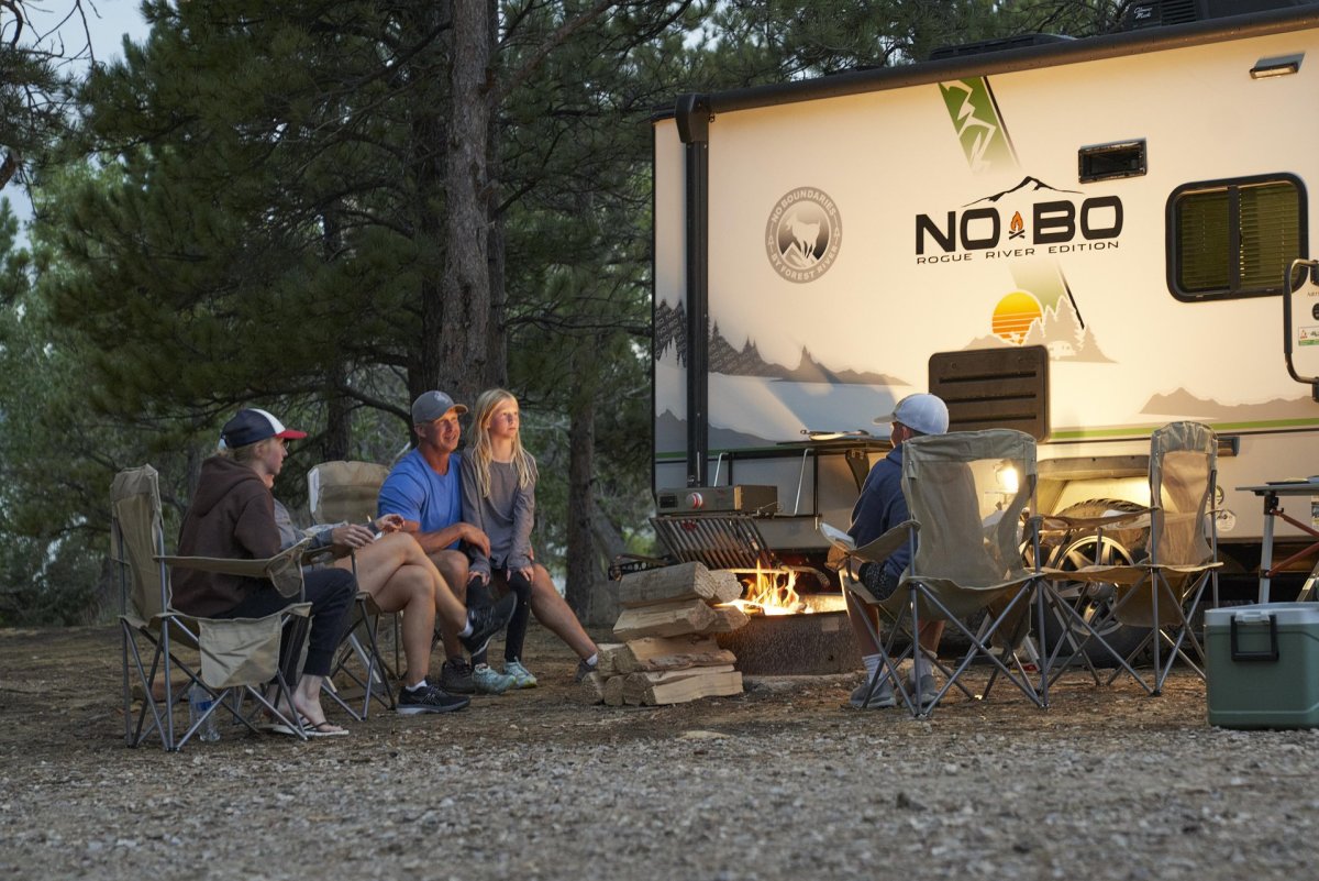 Family sitting around a fire at an RV site.