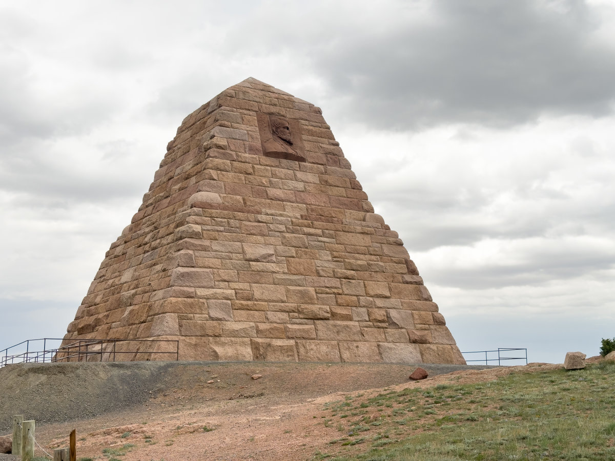 A stone pyramid stands on a mound in grassy plains, a weird and unique place to visit in Wyoming.
