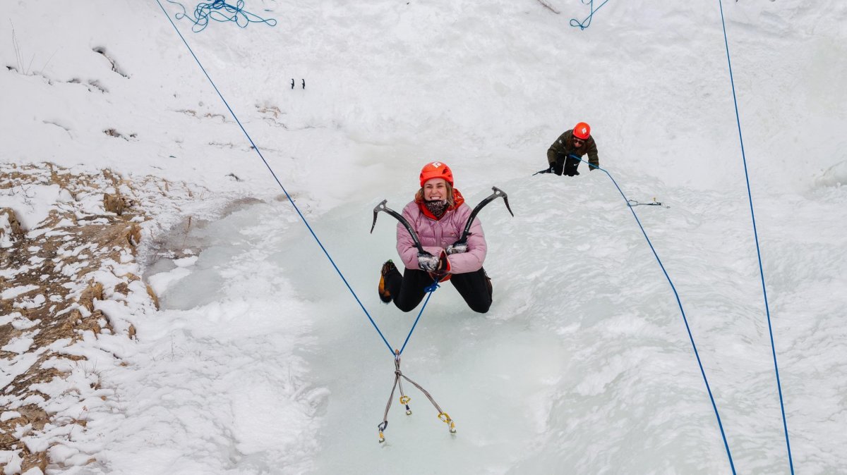 Woman using ice climbing equipment to climb in Cody.