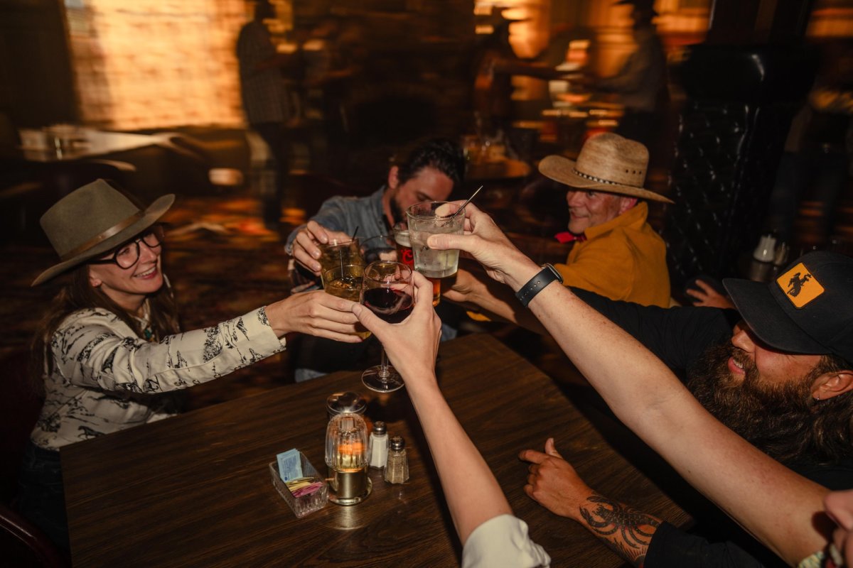 Group of people cheersing drinks around a table.