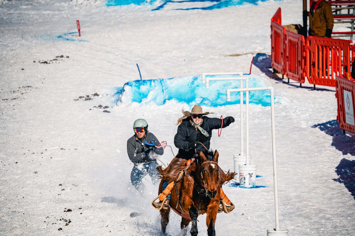 Horse and rider pulling man on skis for skijoring at the Wyo Rodeo.