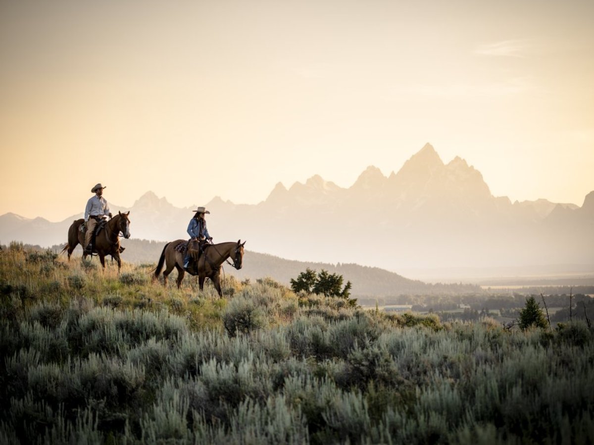 Riders on horses on a foggy morning in front of the tetons