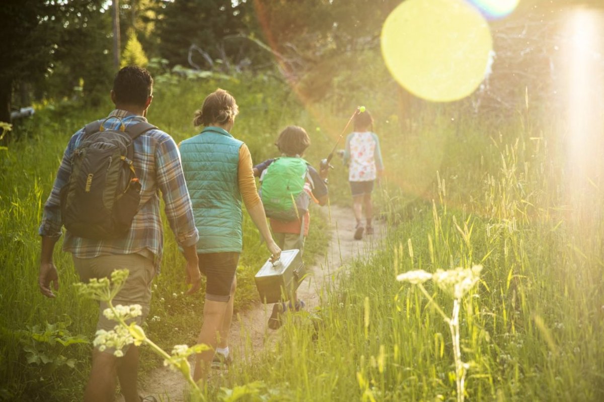 Family walking through grass with fishing equipment in Wyoming