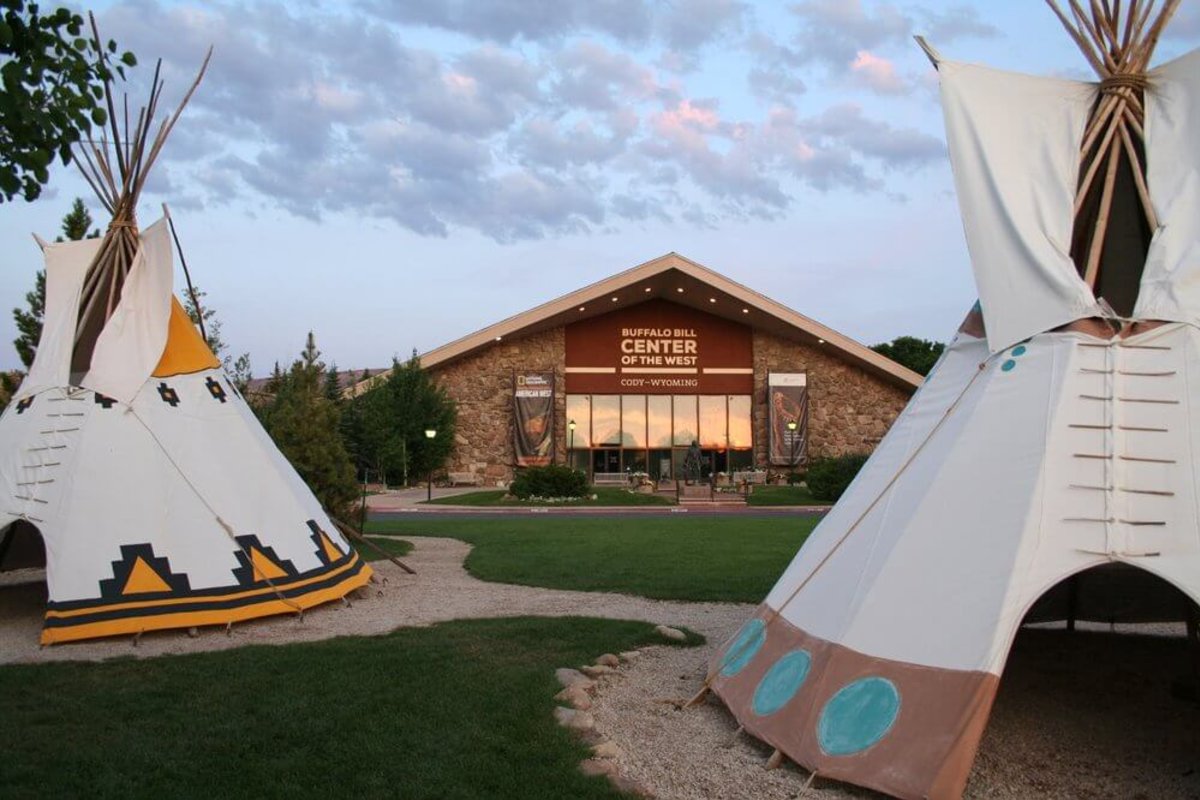 Two teepees in the foreground and the Buffalo Bill Center of the West in the background.