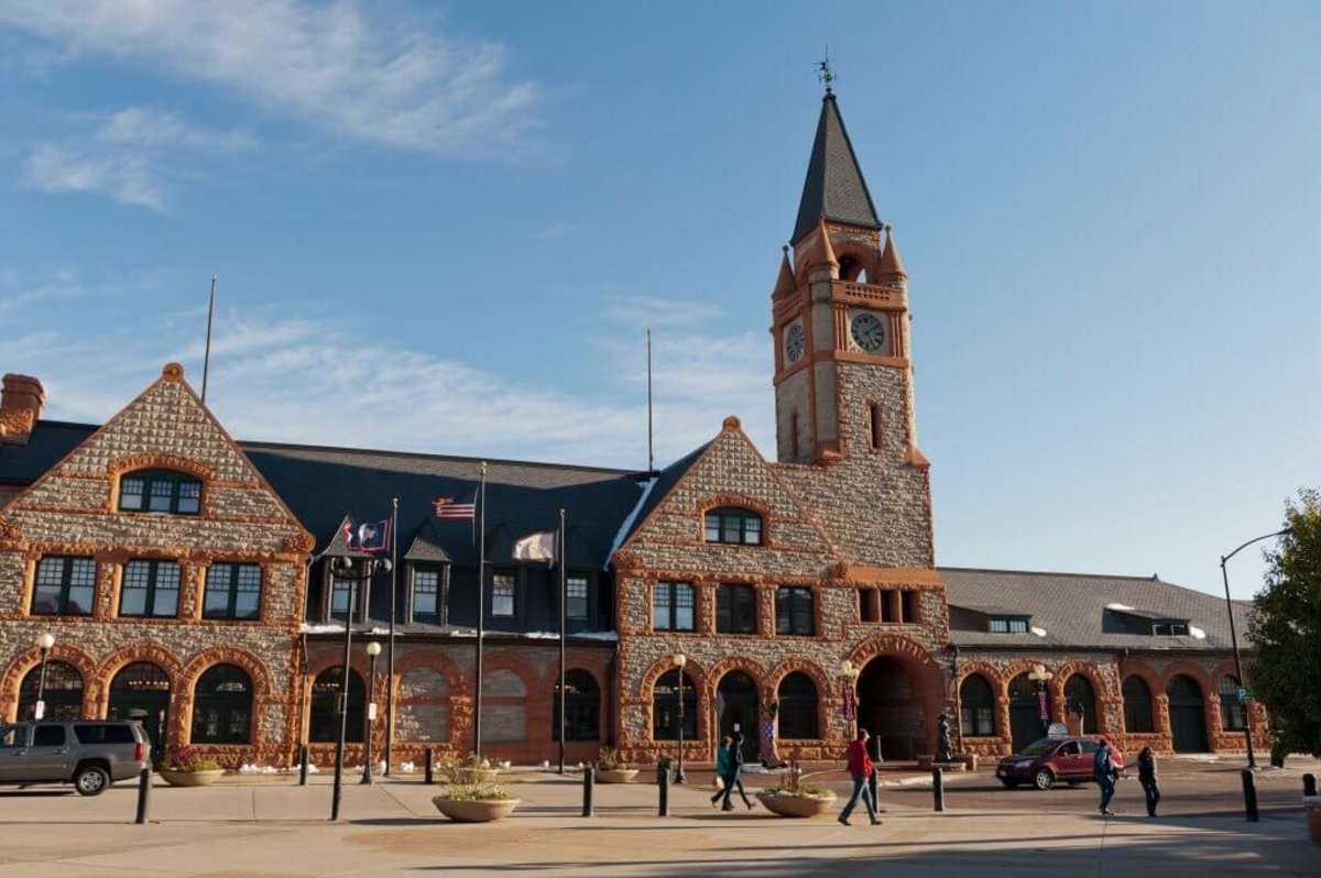 A handful of people and cars going past the front of the Cheyenne Depot Museum.