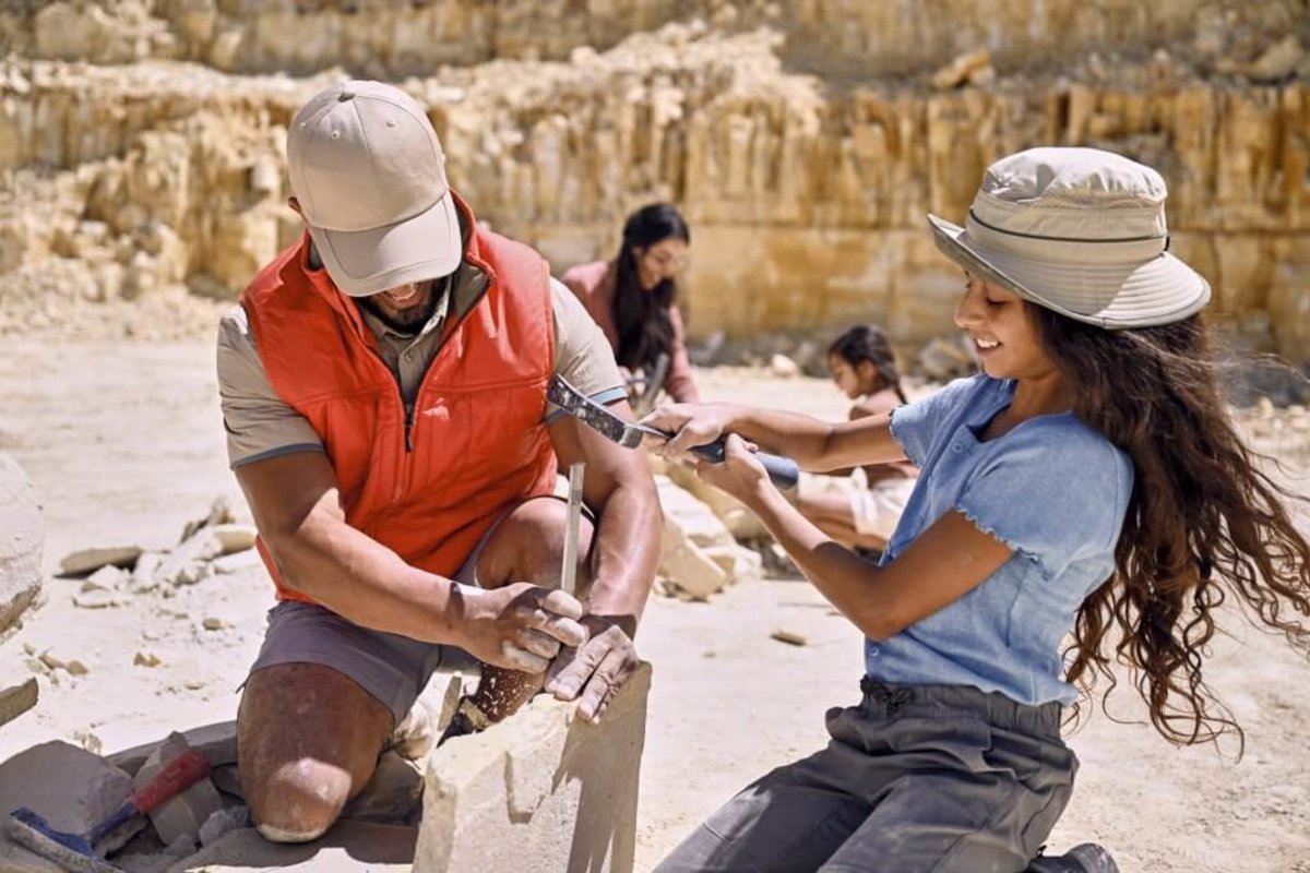 A family of four digging for fossils and a rugged rock formation in the background at Fossil Lake.