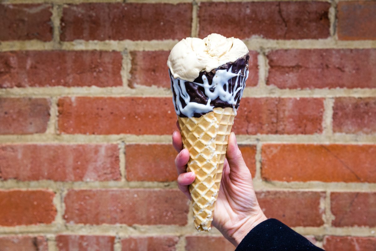vanilla ice cream with a chocolate-dipped cone in front of a brick wall