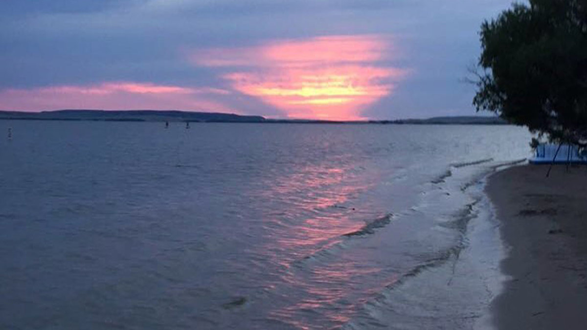 The sun sets in pink and blue colors over Glendo Reservoir, a large body of water great for ice fishing in Wyoming.
