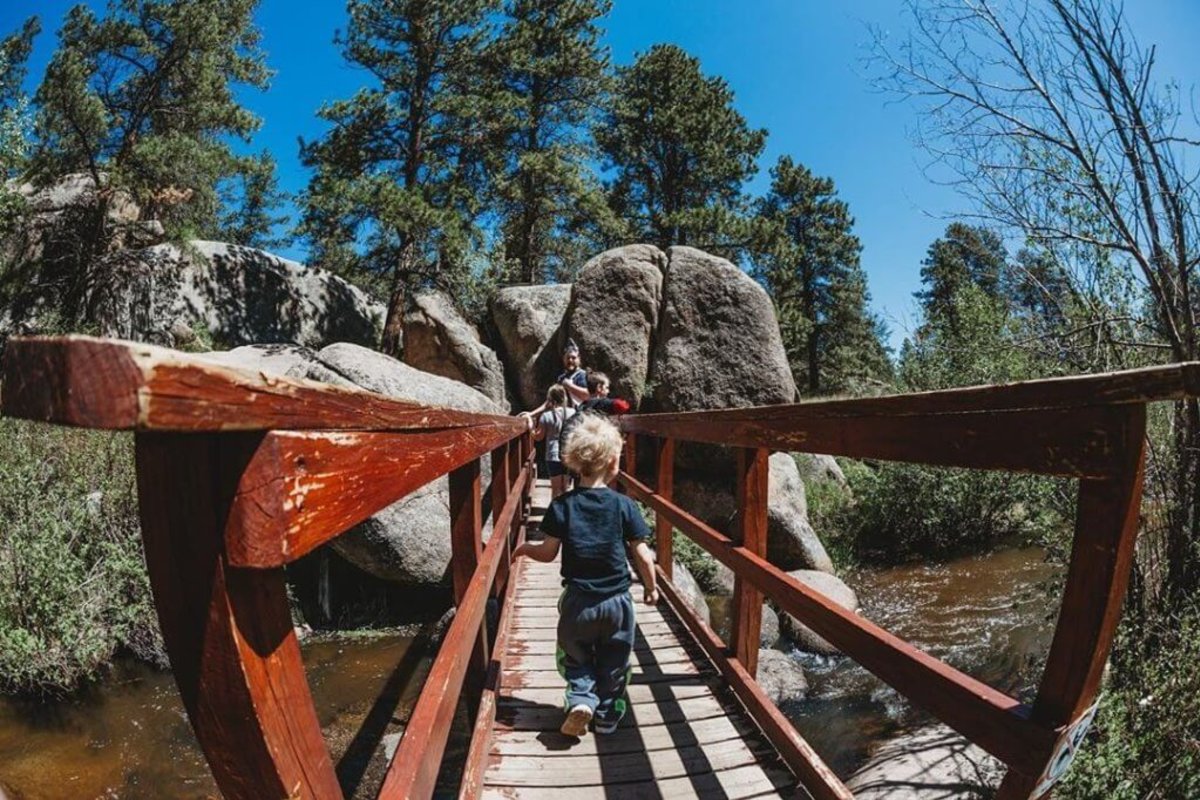 A family walks giddily exploring across a bridge across Crow Creek Trail to Hidden Falls.