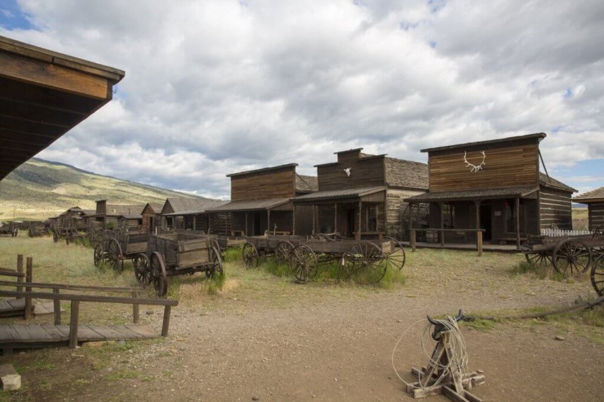 Wooden wagons rest their wheels in the grass in front of buildings at the Museum of the Old West at Old Trail Town in Cody, Wyoming.