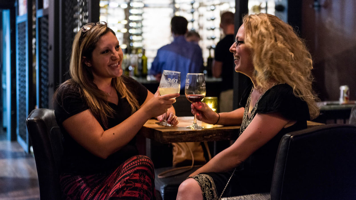 Women laugh and enjoy glasses of wine at Western Wineries 307 wine bar, a popular place to go in Sheridan.