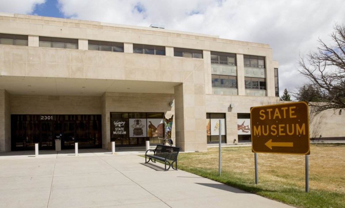An outside view of the Wyoming State Museum and a sign that reads, "State Museum" in the foreground.