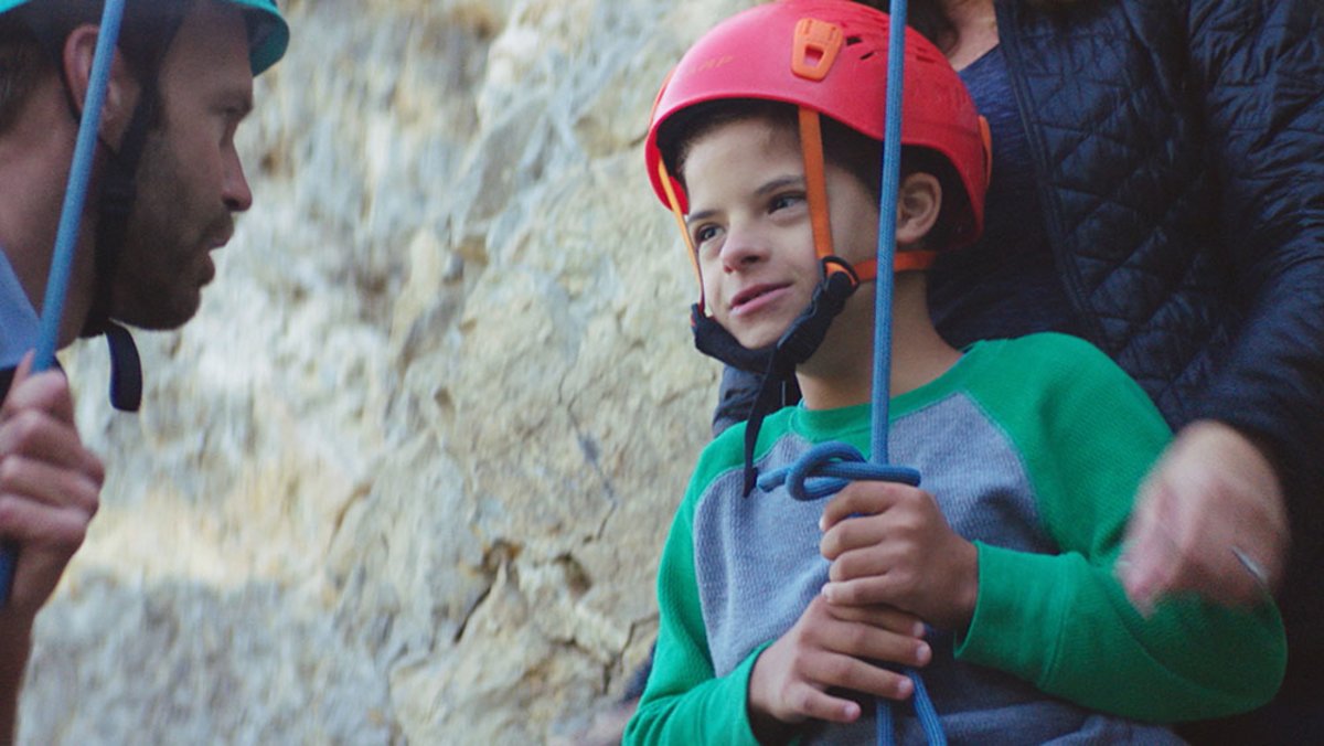 Little boy receiving instruction before beginning to rock climb