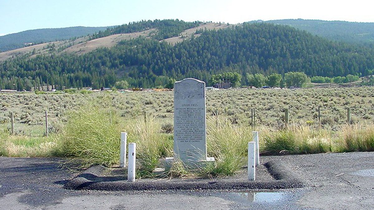 a memorial in front of a green mountain range at Union Pass Monument, a historic road trip stop
