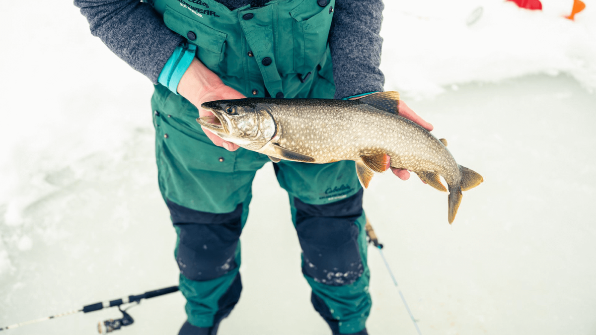 Angler ice fishing on a frozen lake with fish in hands in Wyoming.