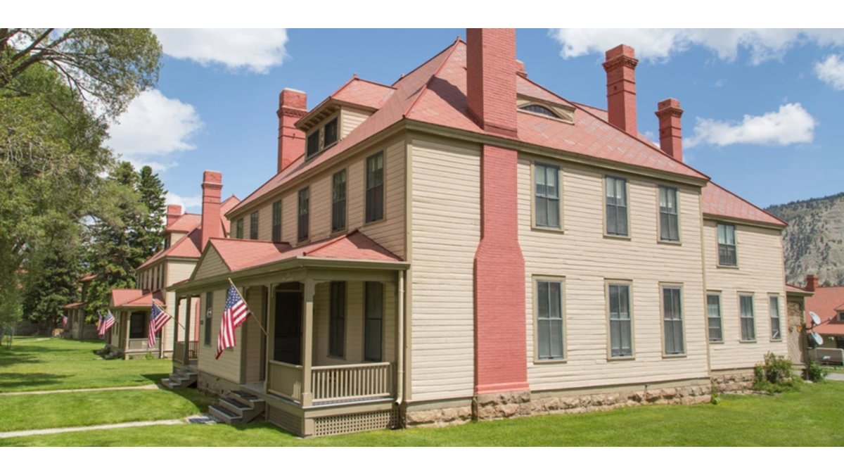 Two historic buildings surrounded by grass lawns and trees at Fort Yellowstone.