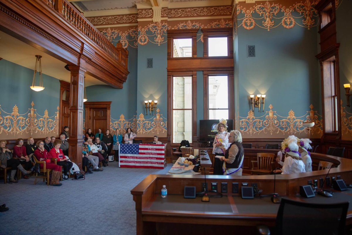 Women gathering in historic courtroom setting.