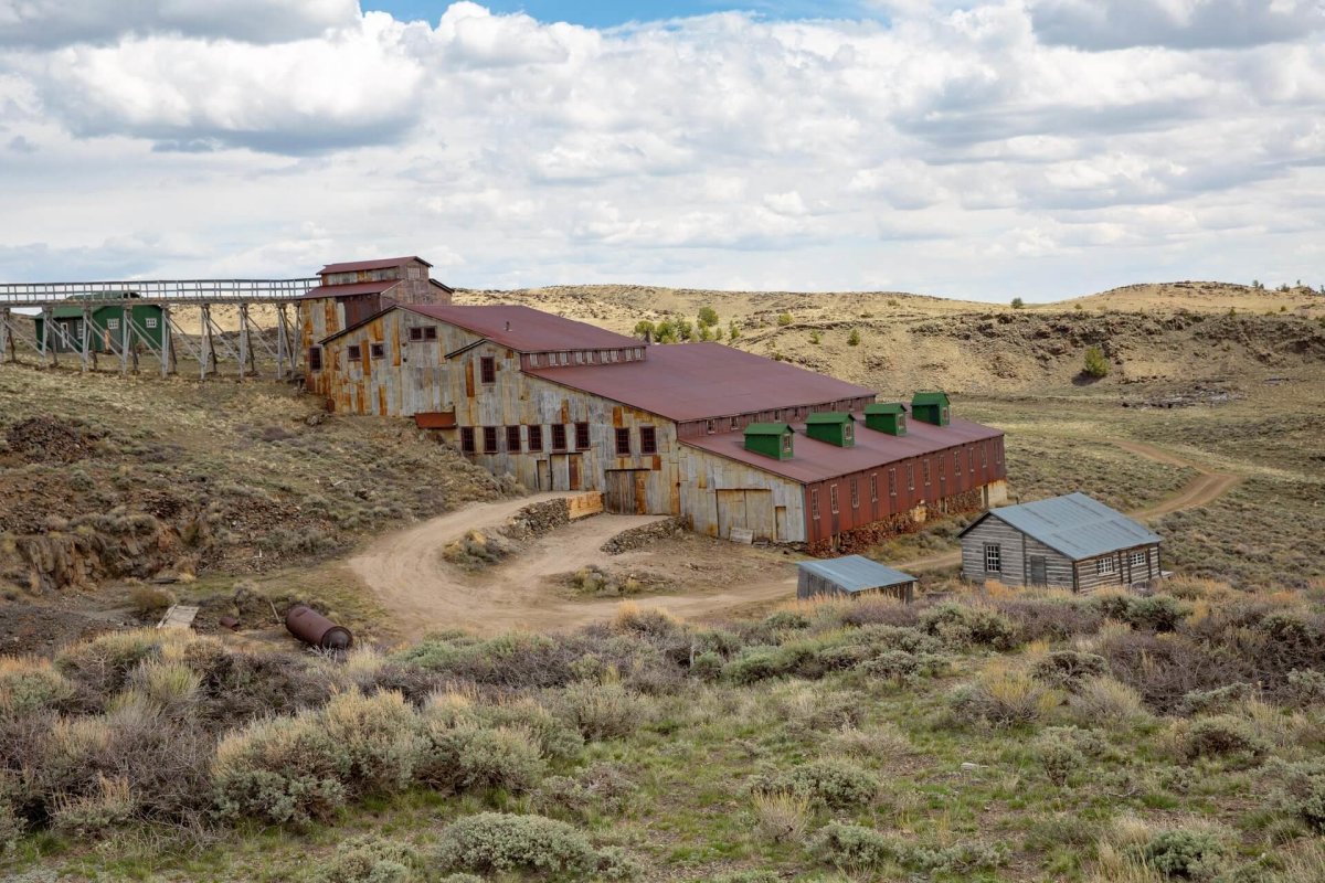 Historic structures from Carissa Mine at South Pass City, surrounded by a landscape of desert brush and hills.
