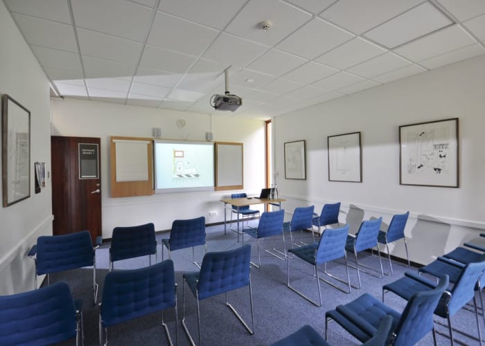 A small training room featuring an "AV wall" and natural daylight. Conveniently located adjacent to the Wolfson Hall, it can be used for syndicate and break out meetings or as a Press or Green Room during larger events in the Wolfson Hall.