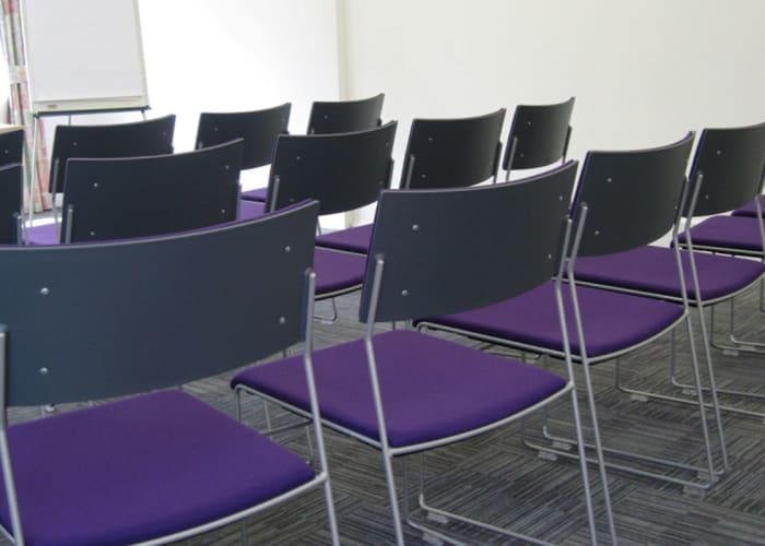 Purple chairs seated theatre style, a layout suitable for presentations and workshops.