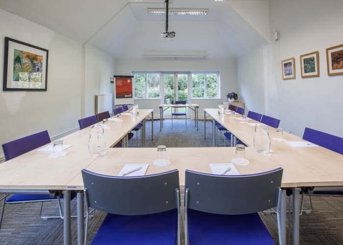 A modern meeting room set u-shape with a large skylight offers natural daylight along with French doors opening onto gardens.