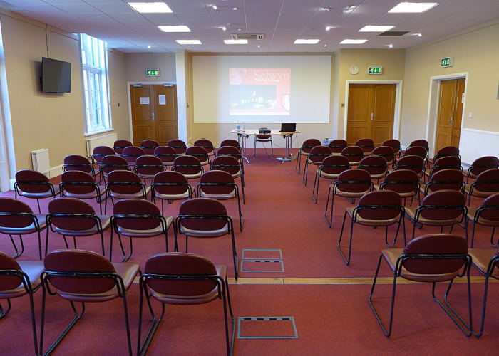 The Chadwick room at Selwyn College, set with rows of chairs with a large screen at the front, ideal for day meetings, lectures and presentations.